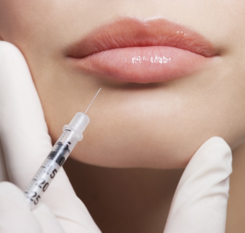 Close up of woman receiving botox injection in lips